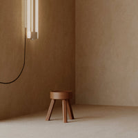 Rustic brown stool on beige floor with minimalist design and warm, soft lighting.