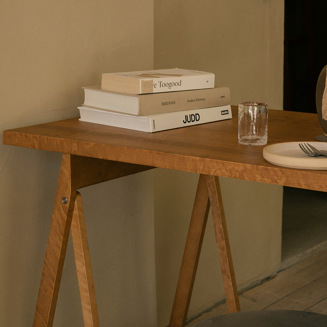Natural wood table with a warm finish, paired with white and beige books, creating a neutral, minimalist aesthetic.