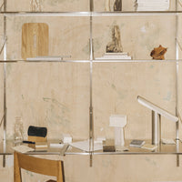 Minimalistic shelf display with neutral tones, soft white accents, and subtle earthy patterns on a textured backdrop.