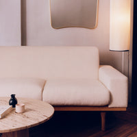 "Neutral cream upholstered sofa with smooth lines, paired with a wooden coffee table and soft ambient lighting."