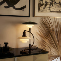 Stylish black and white lamp with glass globe shades, accented by warm light; modern decor with elegant lines.