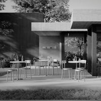 Modern outdoor patio setting with sleek black and gray tones, featuring minimalist furniture and natural greenery.