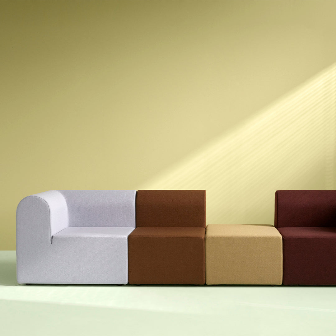 Modern modular sofa featuring soft white, rich brown, warm beige, and deep burgundy fabrics against a pale green backdrop.