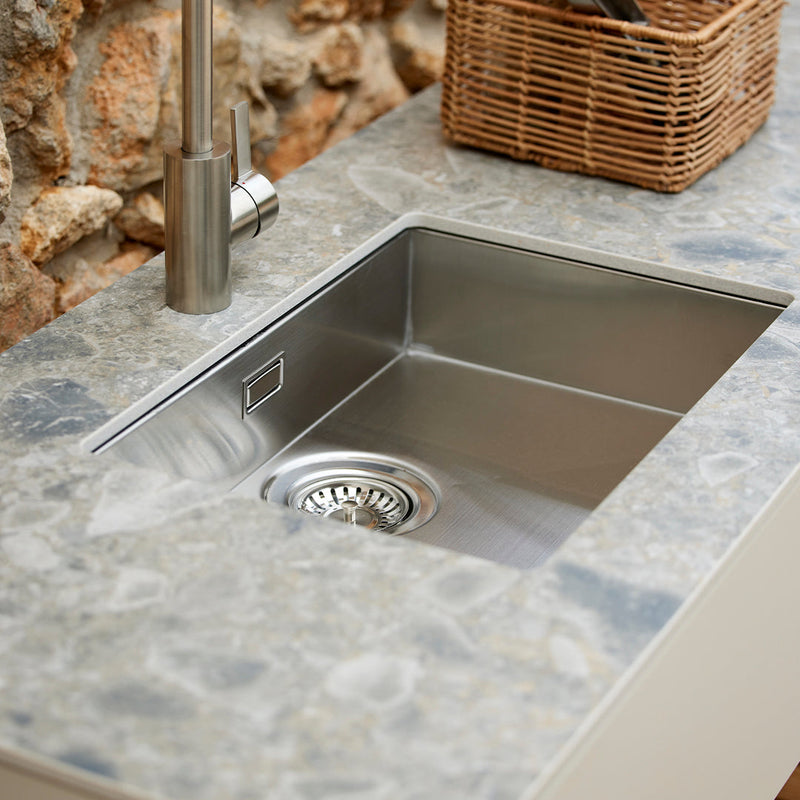 Stylish stainless steel sink with a grey speckled stone countertop featuring earthy tones and natural patterns.