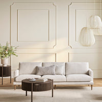 Light gray sofa with a smooth fabric, paired with a dark wood round coffee table and neutral wall decor.
