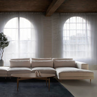 White sectional sofa with subtle texture against a soft gray and dark blue rug, highlighted by natural light.