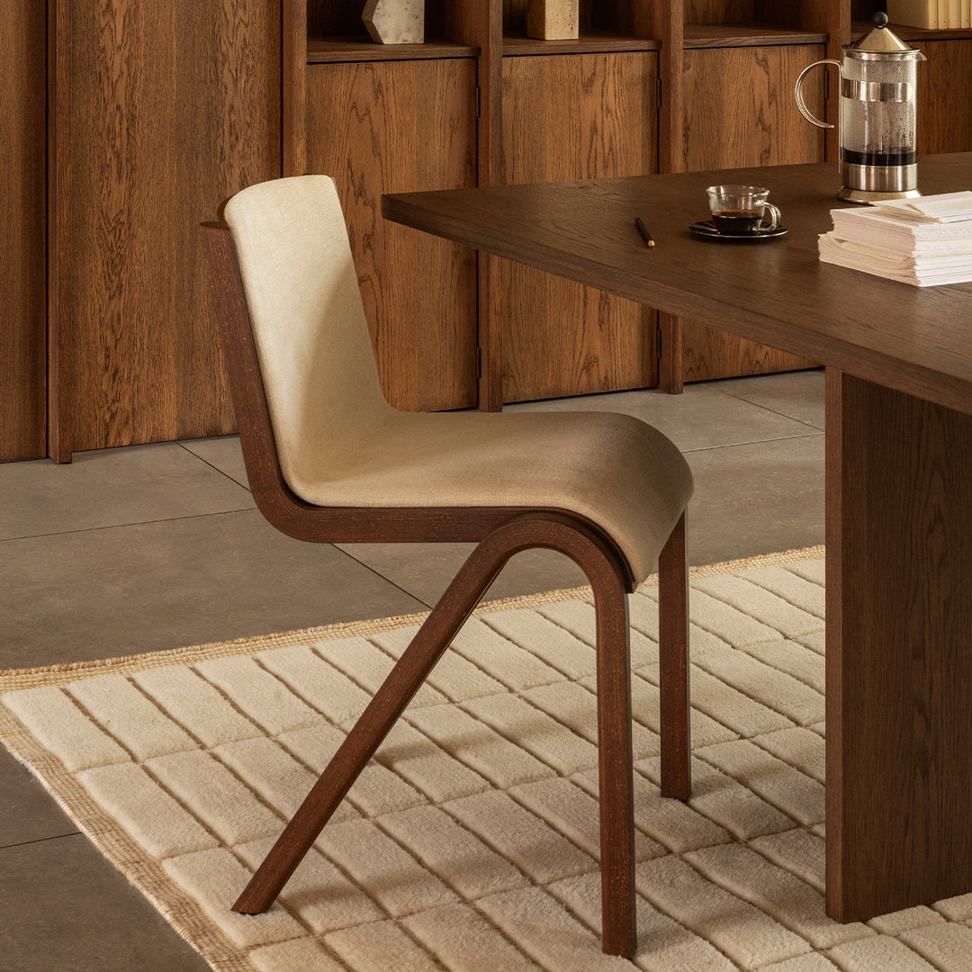 Beige and brown dining chair with a sleek, curved design, set against a minimalist wooden backdrop. Modern and stylish.