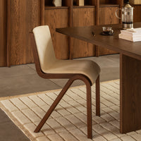 Beige and brown dining chair with a sleek, curved design, set against a minimalist wooden backdrop. Modern and stylish.