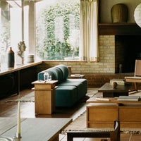 Mid-century modern living room featuring a teal sofa, wooden furniture, and neutral-toned decor elements.