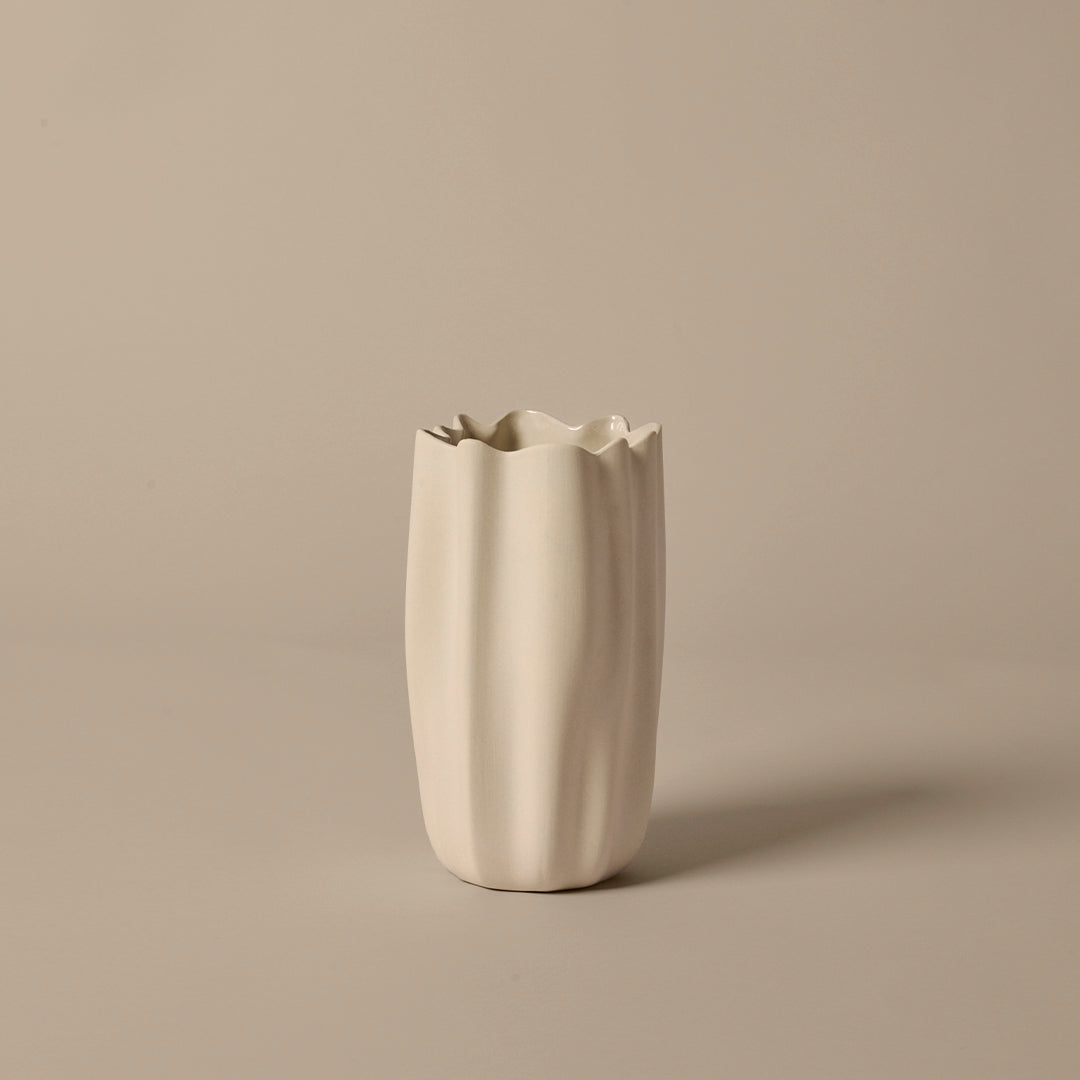 White textured vase with a wavy pattern, featuring unique fluted edges against a beige background.