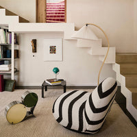 Black and white striped bean bag chair with green and yellow accent pieces in a modern interior setting.