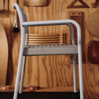 Modern light gray chair with woven pattern seat, against a wooden backdrop with warm, natural tones.