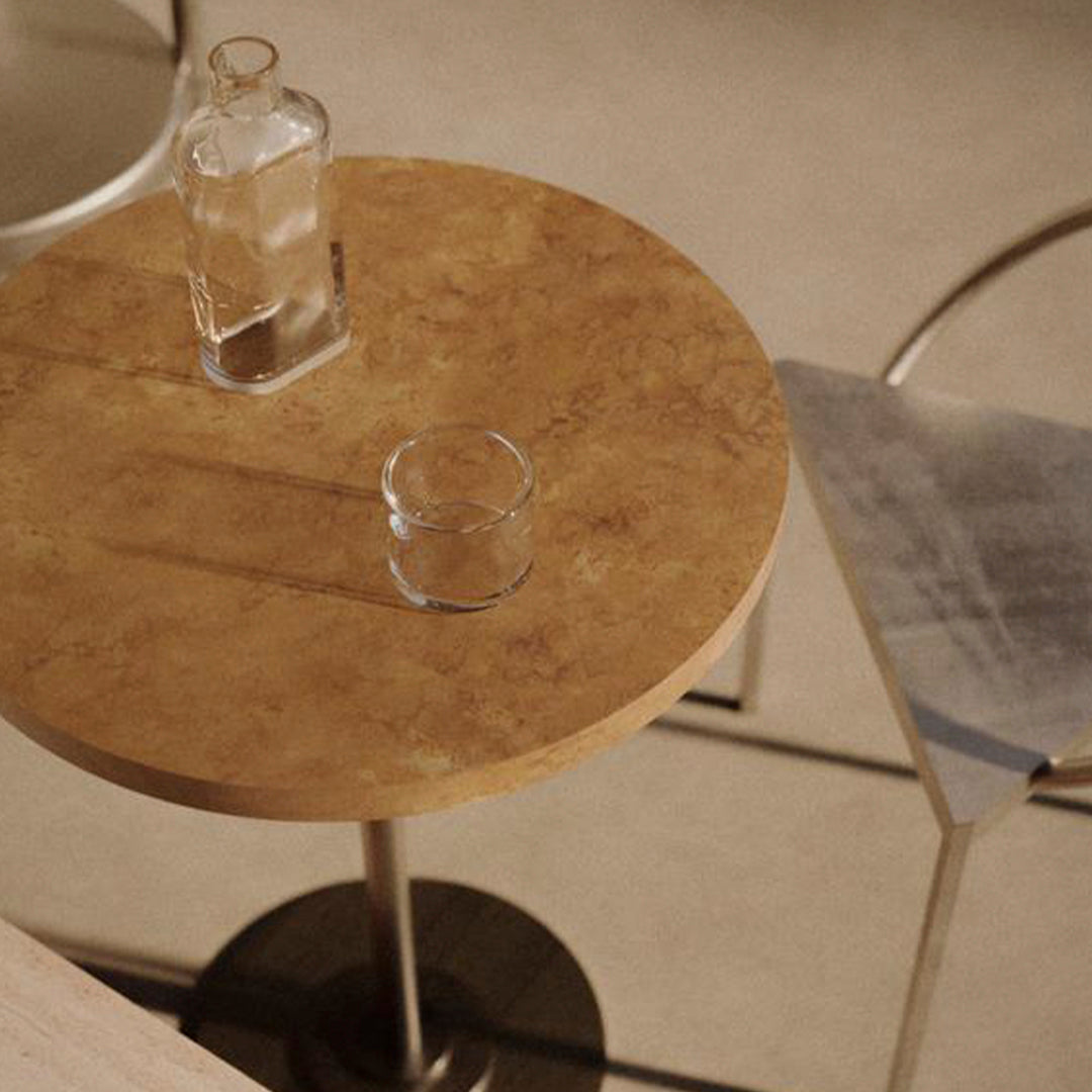 Round brown marble table with a smooth finish, complemented by clear glassware on a neutral background.
