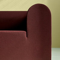Burgundy textured fabric sofa with soft curves against a pale yellow background. Modern, minimalistic design.