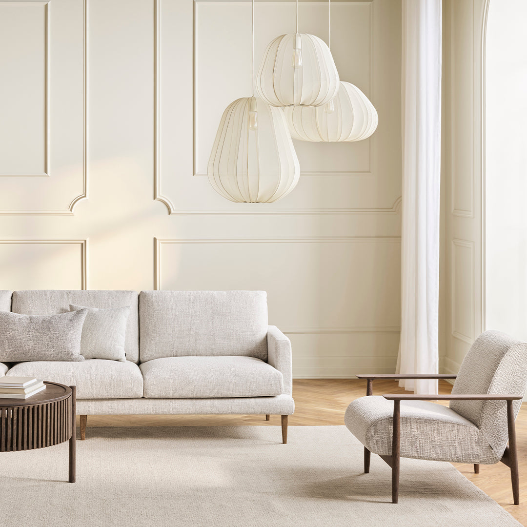 Light beige sofa with subtle texture, paired with a cream armchair and soft, neutral tones in a modern living space.
