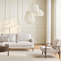 Light beige sofa with subtle texture, paired with a cream armchair and soft, neutral tones in a modern living space.