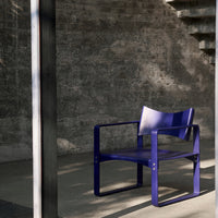 Vibrant purple chair with a minimalist design, set against a textured gray wall. Modern aesthetic and bold color.