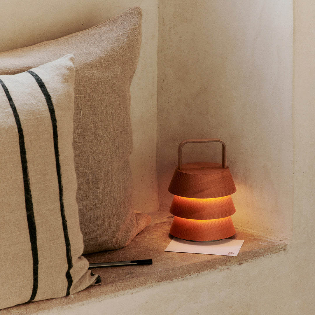 "Modern stacked lantern in warm tones; beige striped pillow complements earthy decor."