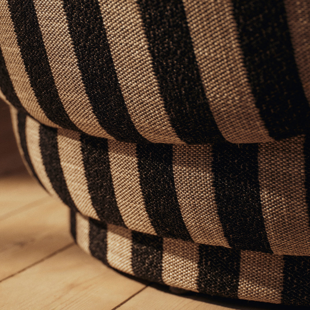 Black and natural striped pattern upholstery on a stylish, rounded furniture piece. Perfect for modern decor.
