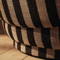 Black and natural striped pattern upholstery on a stylish, rounded furniture piece. Perfect for modern decor.