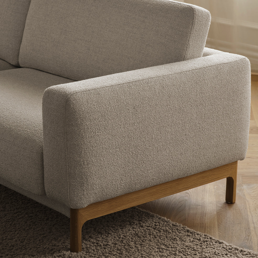 Light beige textured fabric upholstery with a natural wood base, creating a modern and minimalist aesthetic.