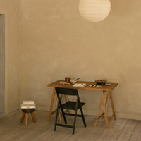 Modern beige walls with a wooden table and black folding chair, complemented by soft, natural tones and textures.