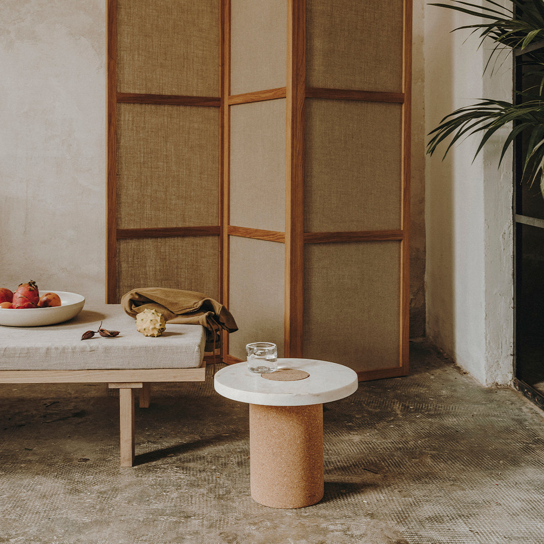Round white marble top with a natural cork base; minimalistic design against neutral earthy tones.