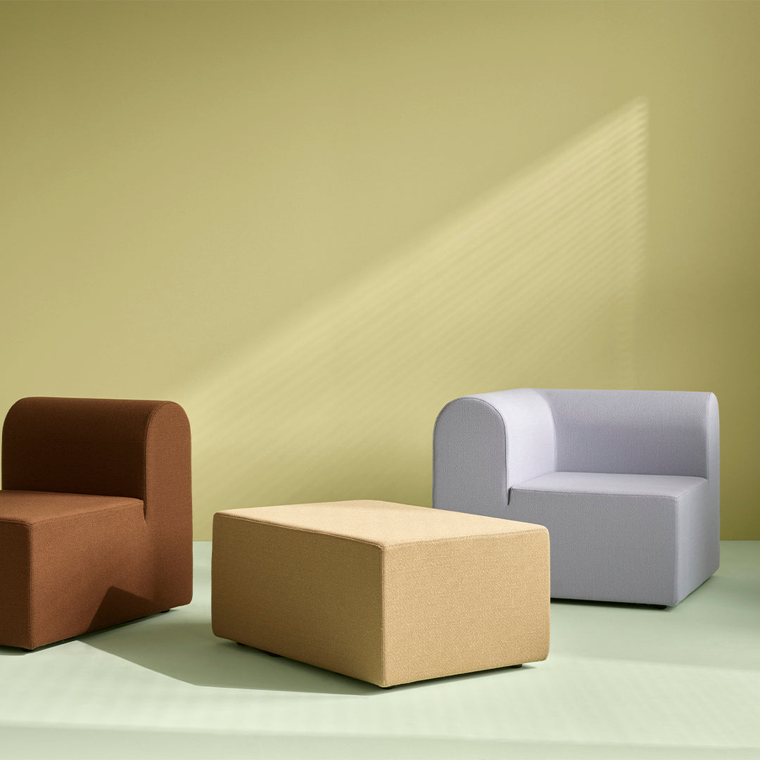 Brown, gray, and beige modern furniture pieces against a muted green backdrop with soft lighting.