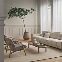 Neutral beige sofa, gray woven chairs, natural wood table, and light cream rug create a serene modern living space.