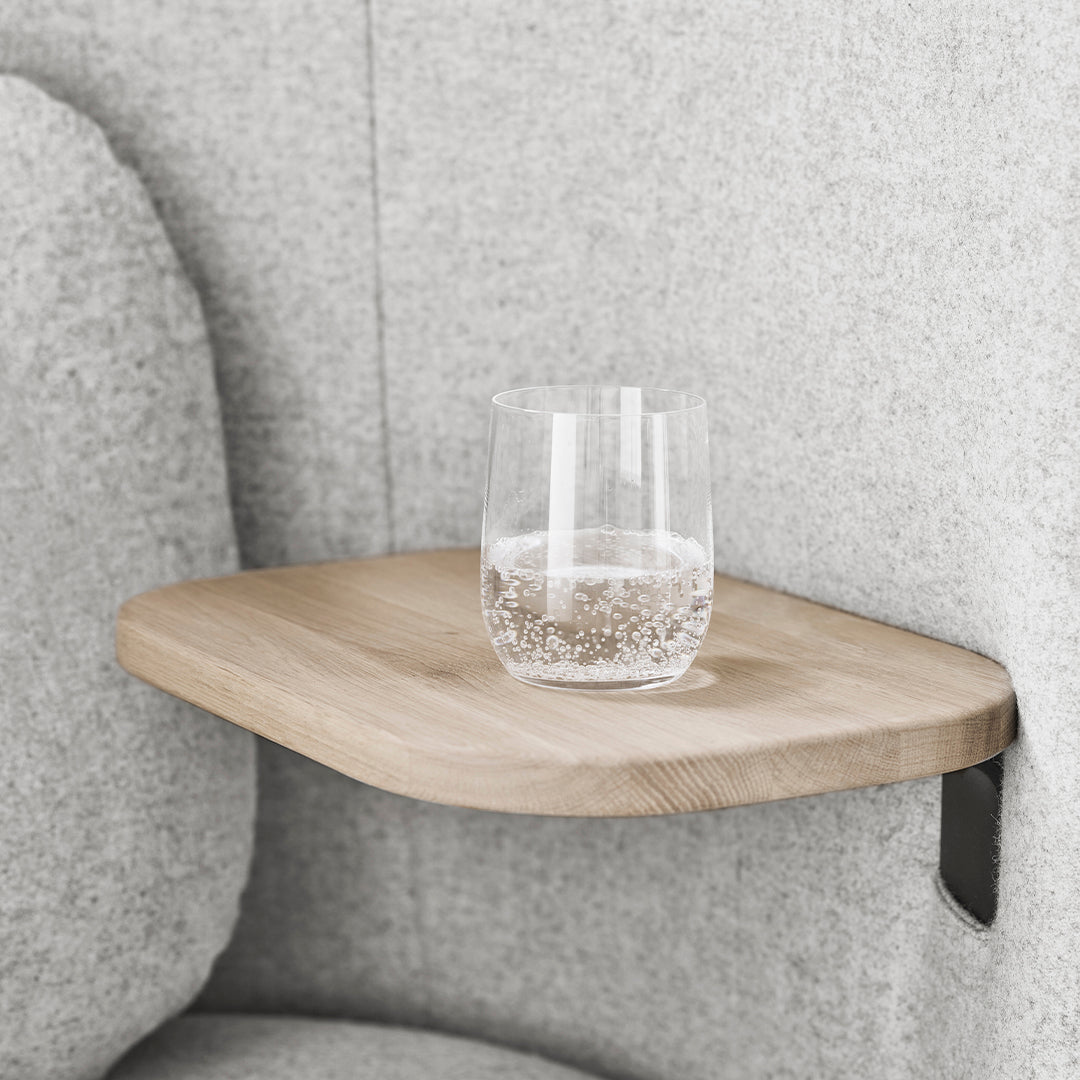 Natural wood shelf with smooth surface, set against soft gray upholstery. Minimalist design enhances modern decor.