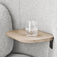 Natural wood shelf with smooth surface, set against soft gray upholstery. Minimalist design enhances modern decor.
