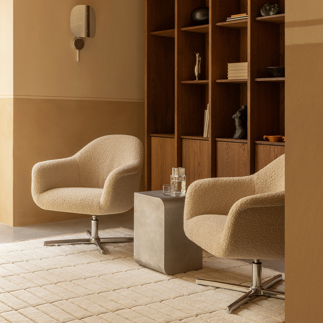 Beige textured armchairs with soft curves, paired with a concrete table in a warm-toned, minimalist setting.