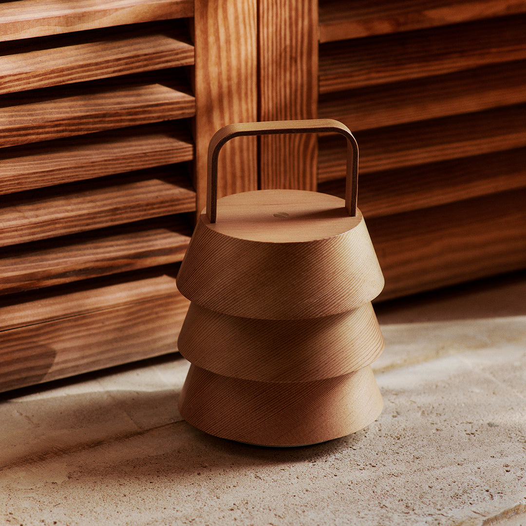 Stacked wooden design with a warm, natural finish and smooth, curved layers; features a sleek metal handle.