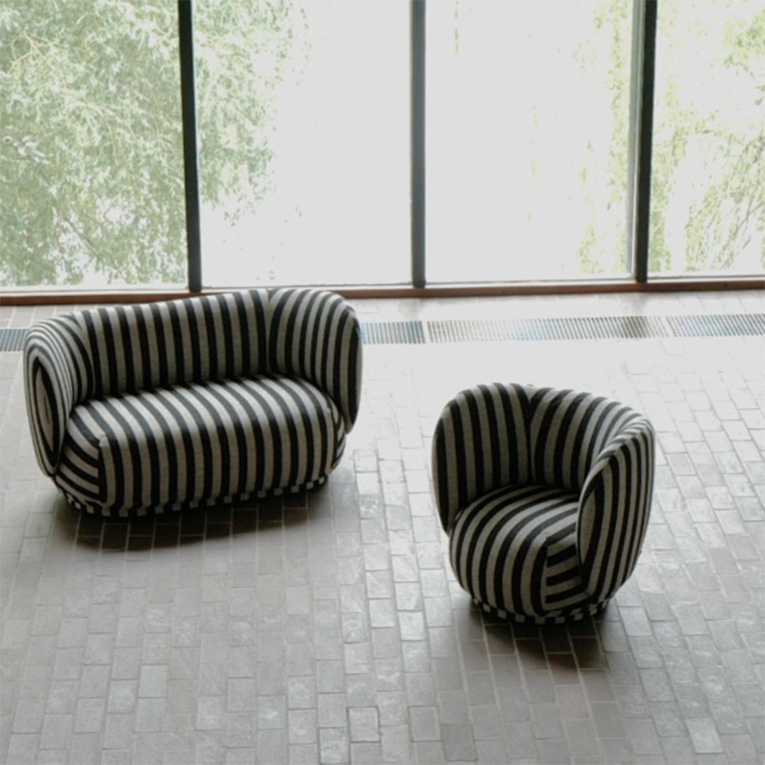 Black and white striped sofa and armchair in modern interior setting.