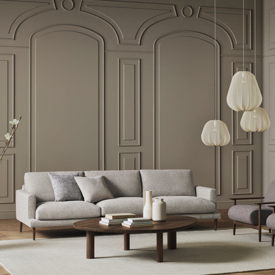 Light gray sofa with matching throw pillows, warm wood accents, and textured beige walls in a modern setting.