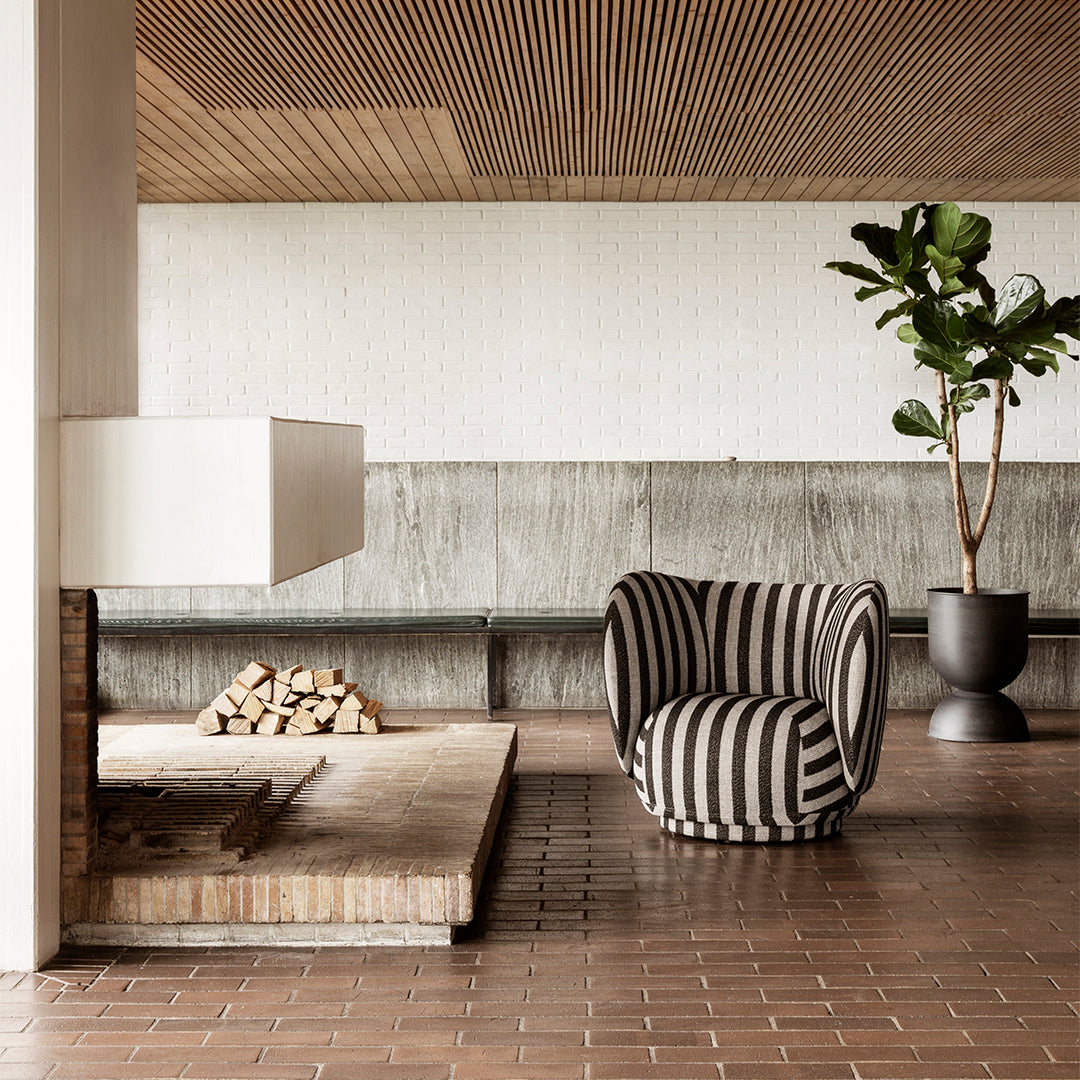 Black and white striped patterned chair in a modern, earthy-tone interior with wood and concrete accents.