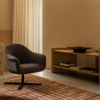 Stylish dark gray upholstered chair on a brown textured rug, complemented by soft beige walls and light curtains.