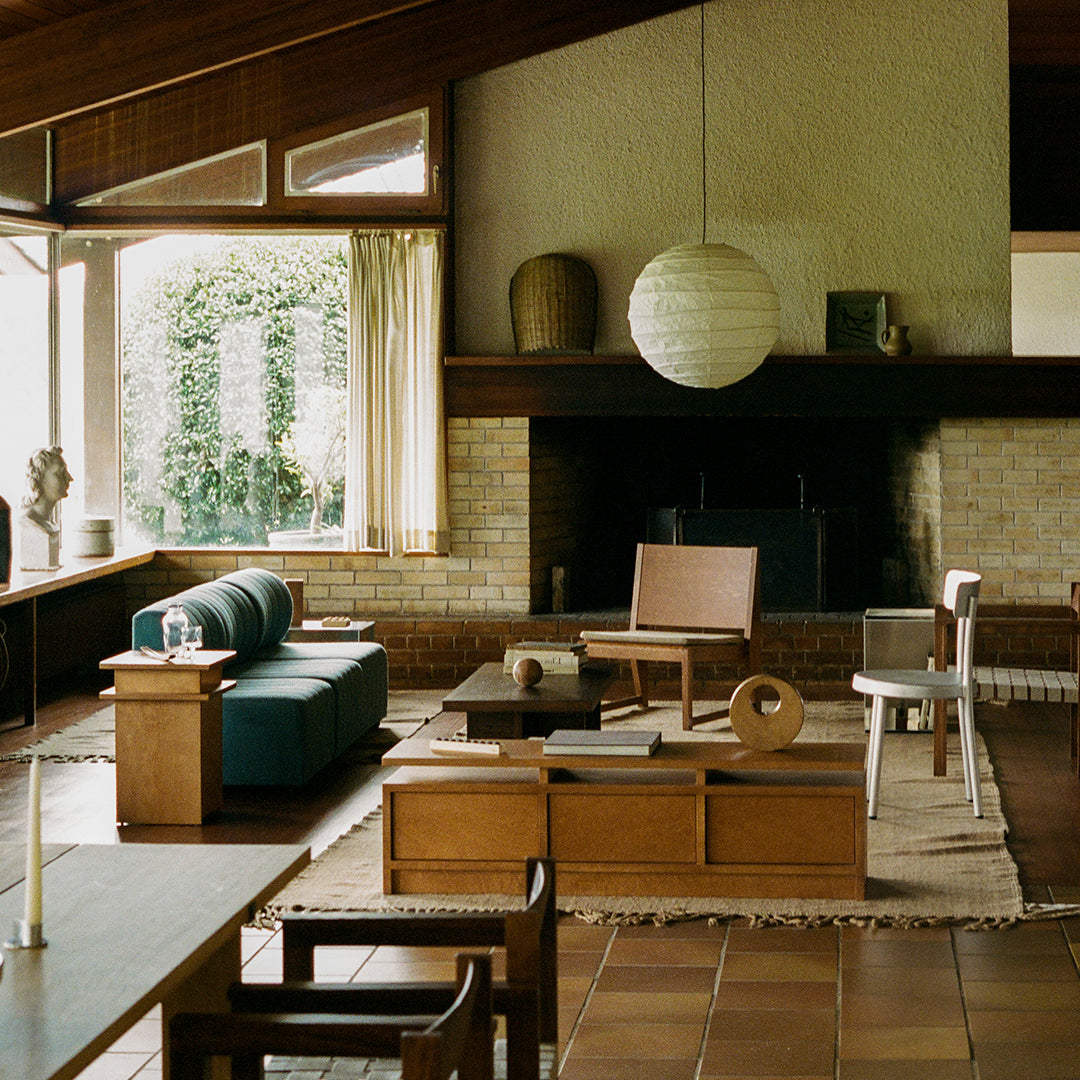 "Mid-century modern living room with teal sofa, natural wood accents, and a neutral woven rug."