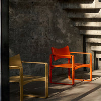 "Two modern chairs in vibrant orange and soft yellow, set against a textured gray backdrop with bold shadows."