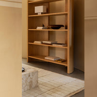 Natural wood shelving unit with a minimalist design, accented by neutral tones and a subtle geometric pattern.