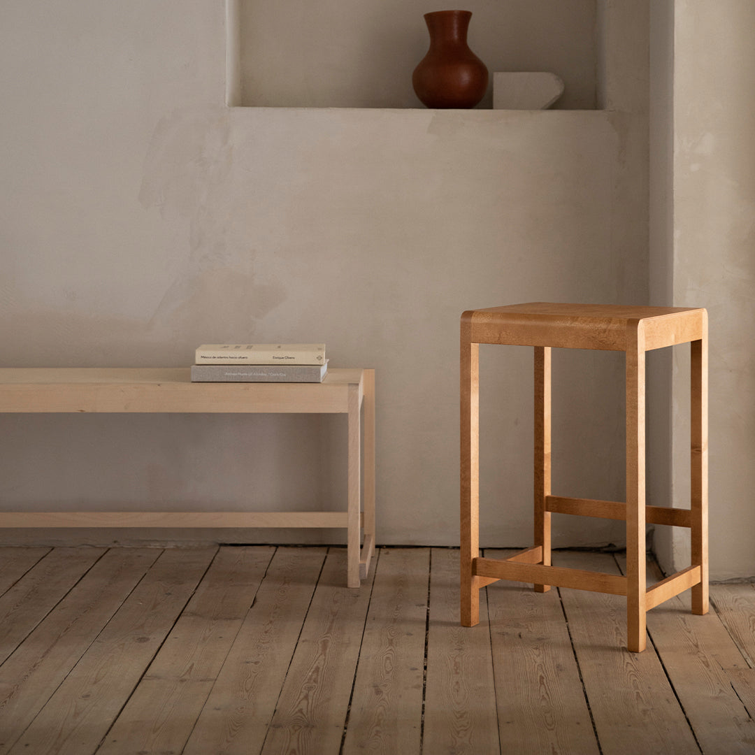 Light wooden furniture set with soft, natural tones against a minimalist beige wall and rustic wooden floor.