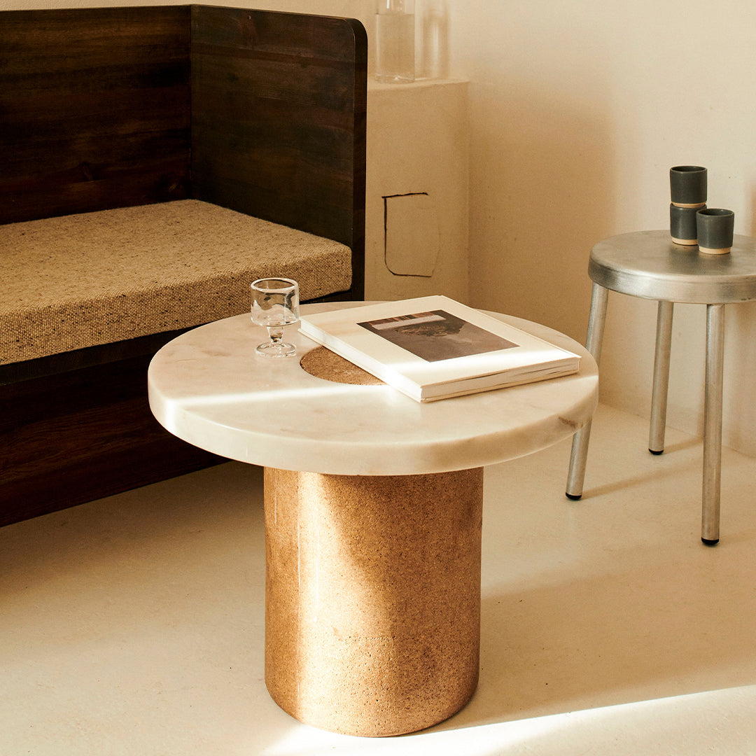 Marble top coffee table with a warm, natural cork base; minimalist design in neutral tones and soft textures.