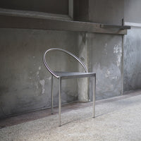 Modern metallic chair with a sleek, minimalistic design featuring a circular backrest and a glossy finish.
