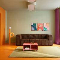 Brown checkered sofa in a vibrant orange and green room with pastel artwork and a pastel pink coffee table.