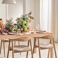 "Elegant dining table set with a floral centerpiece featuring vibrant colors and soft textures in a light, airy room."