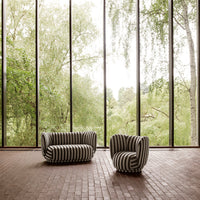 Black and white striped sofa and chair set against a backdrop of lush greenery and natural light.