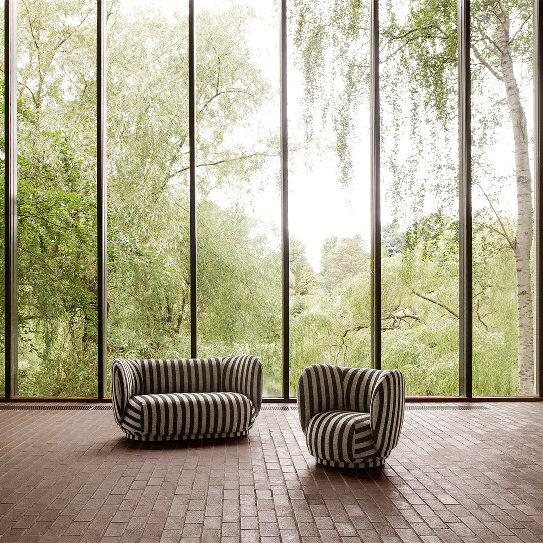 Black and white striped sofa and chair in a bright, airy setting with large windows and greenery outside.