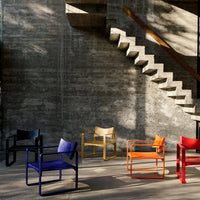 Colorful modern chairs in black, blue, yellow, orange, and red displayed against a concrete backdrop and patterned stairs.