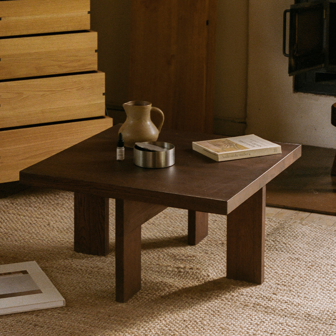 Dark wood square coffee table with a minimalist design, featuring natural textures and a warm, earthy color palette.
