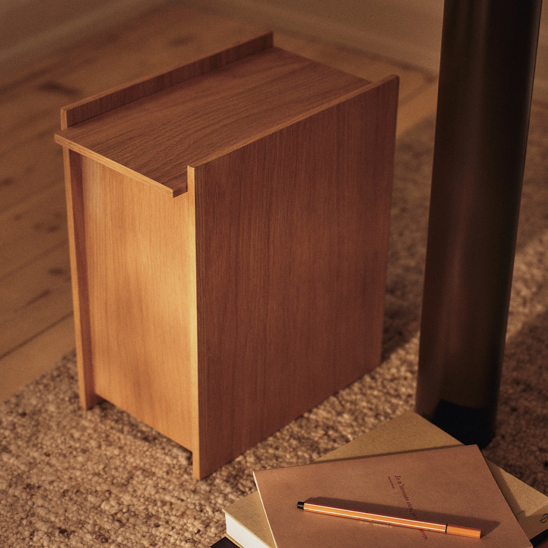 Wooden side table in a warm, natural finish with a sleek design and minimalistic patterns, set against a soft rug.